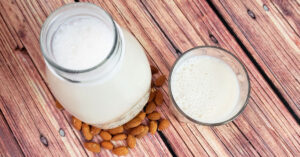 Homemade almond milk in a glass jar next to a full glass.