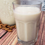 Glass of homemade almond milk in front of bottle.