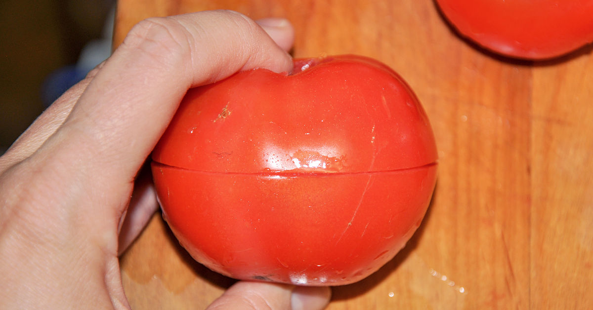Tomato with a score made around the entire tomato with a sharp paring knife.
