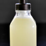 Clear glass foaming soap pump filled with homemade hand soap on a dark background