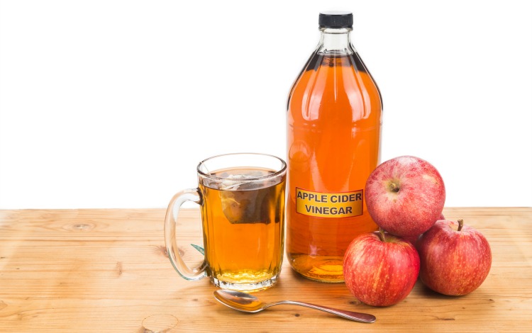 Apple Cider Vinegar on a table with apples and a tea cup