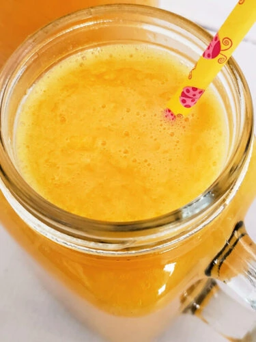 Close up of pint glass of fermented orange juice in front of mason jar of remaining drink