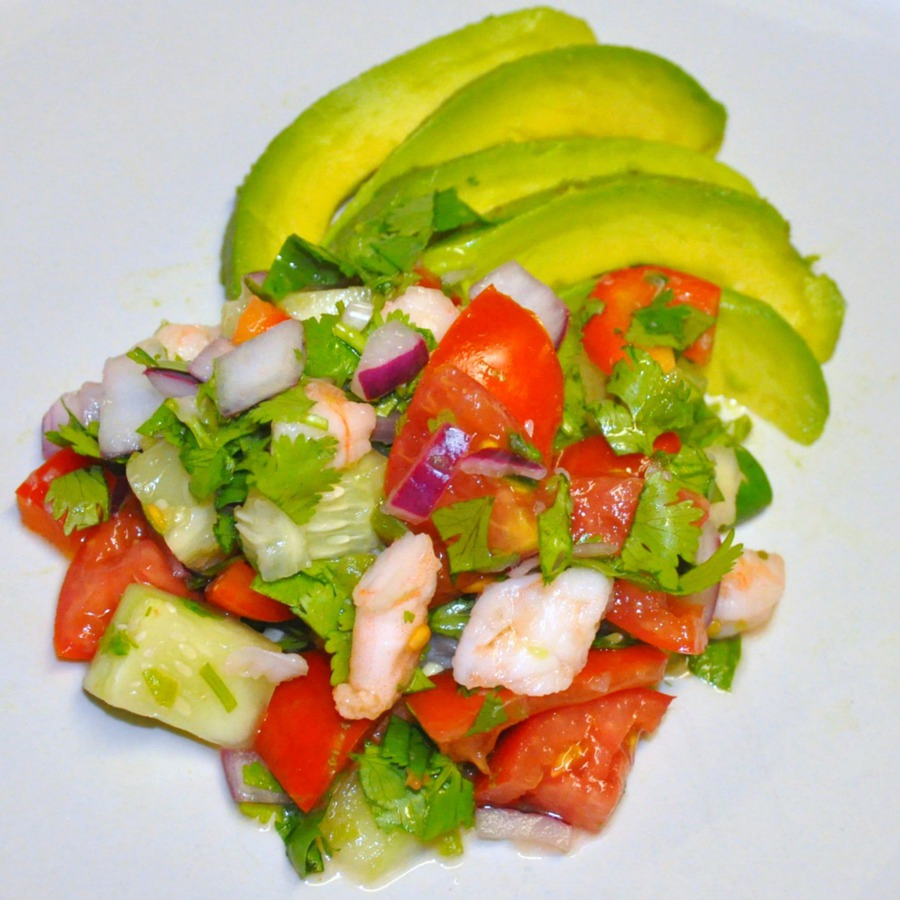 Overhead view of shrimp ceviche with avocado slices on white dinner plate