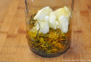 Dried calendula and lavender flowers in a glass jar with olive and coconut oil
