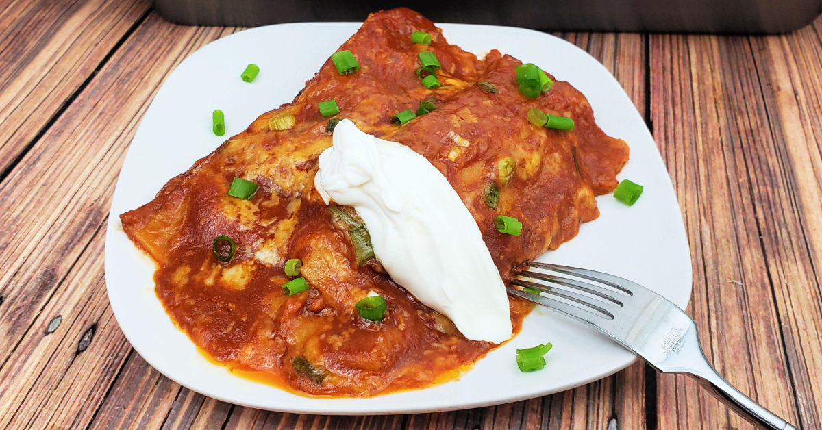 Chicken enchiladas topped with sour cream and green onions.