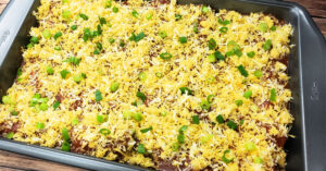 Shredded cheese and green onions sprinkled over the top of homemade chicken enchiladas.