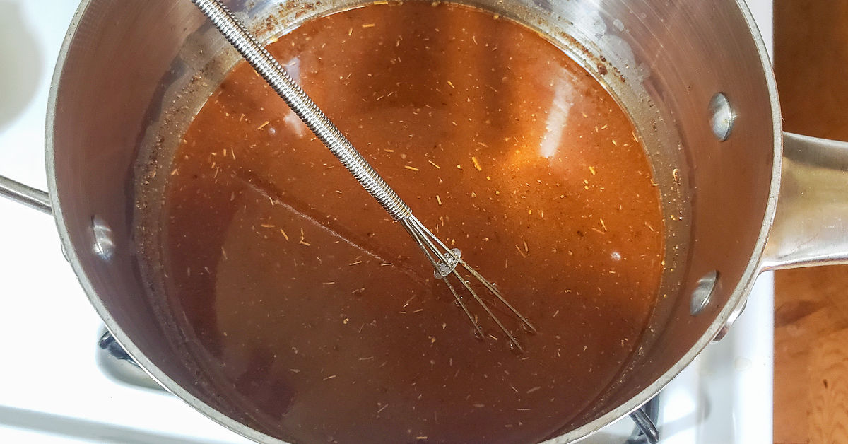 Chicken stock being whisked into spices and butter.