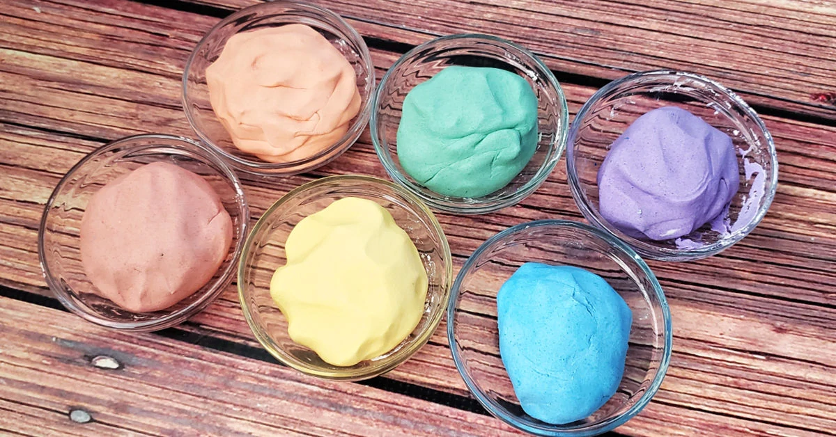 Cloud dough being colored with mica powder in small glass bowls.