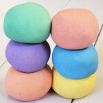 Close up of 6 balls in homemade cloud dough in rainbow colors.