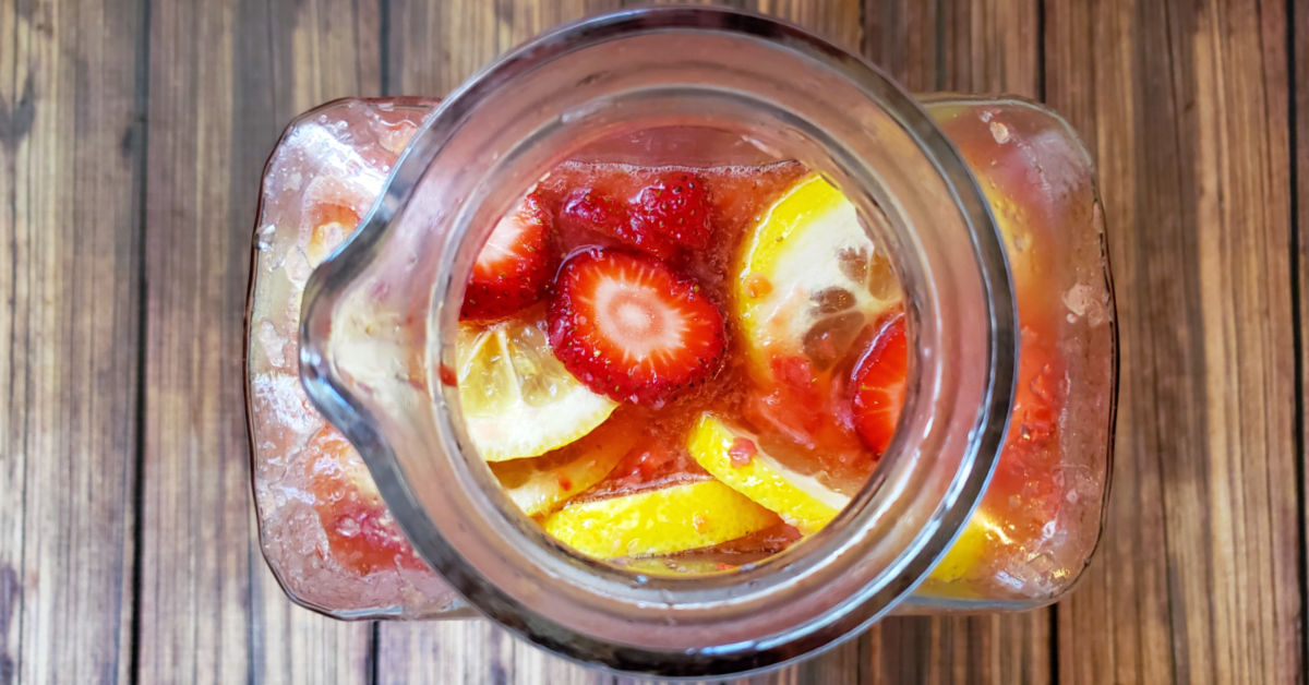 Overhead view of pitcher filled with fresh homemade strawberry lemonade with lemon and strawberry slices in it.