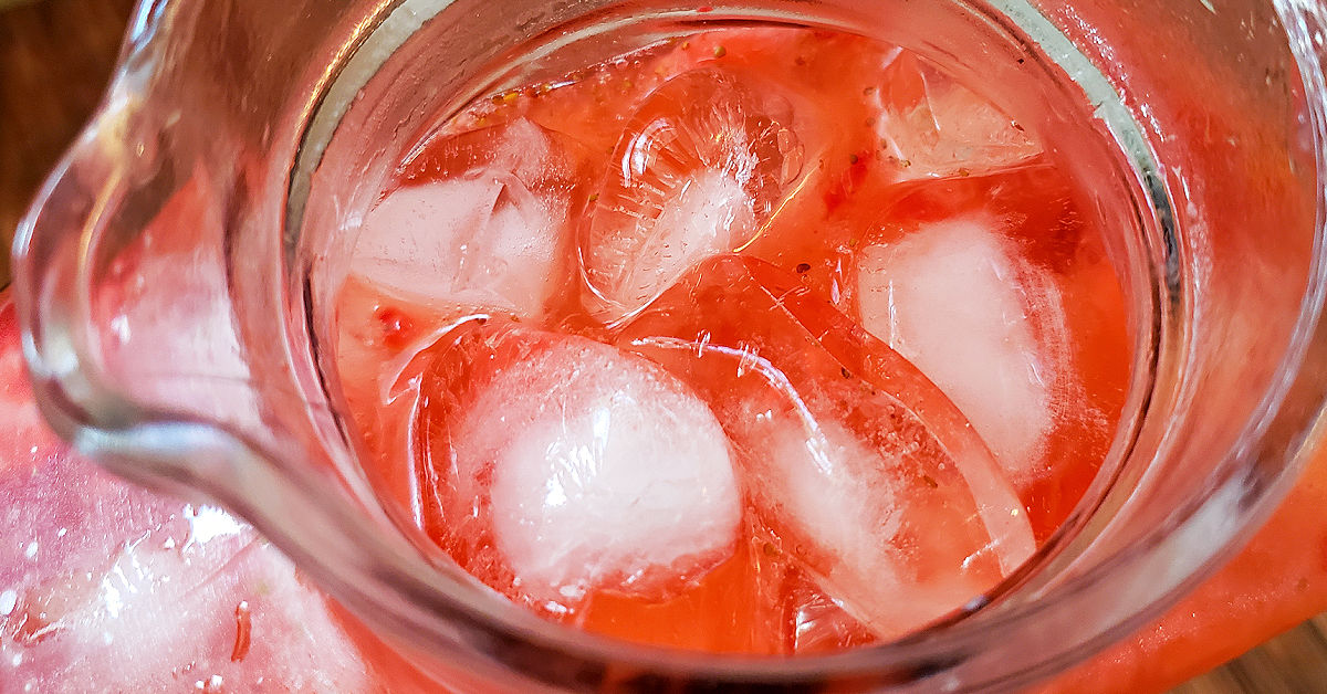 Strawberry lemonade with ice in a pitcher.