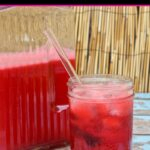 Pint and pitcher of Cherry Limeade on blue painted wood table and bamboo background
