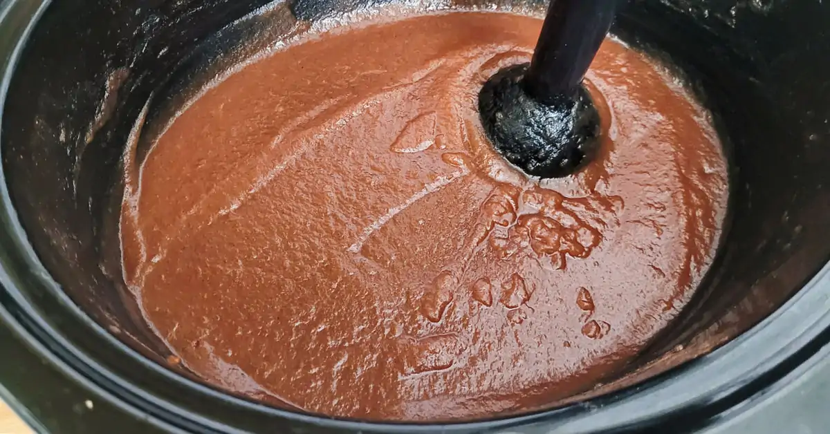 Apple butter being pureed with an immersion blender.