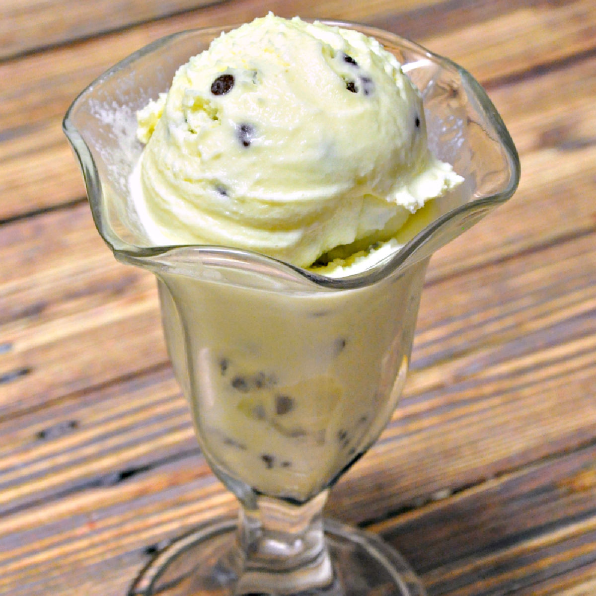 Mint chocolate chip ice cream served in a glass parfait dish.