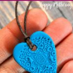 Blue heart clay essential oil diffuser necklace in a hand