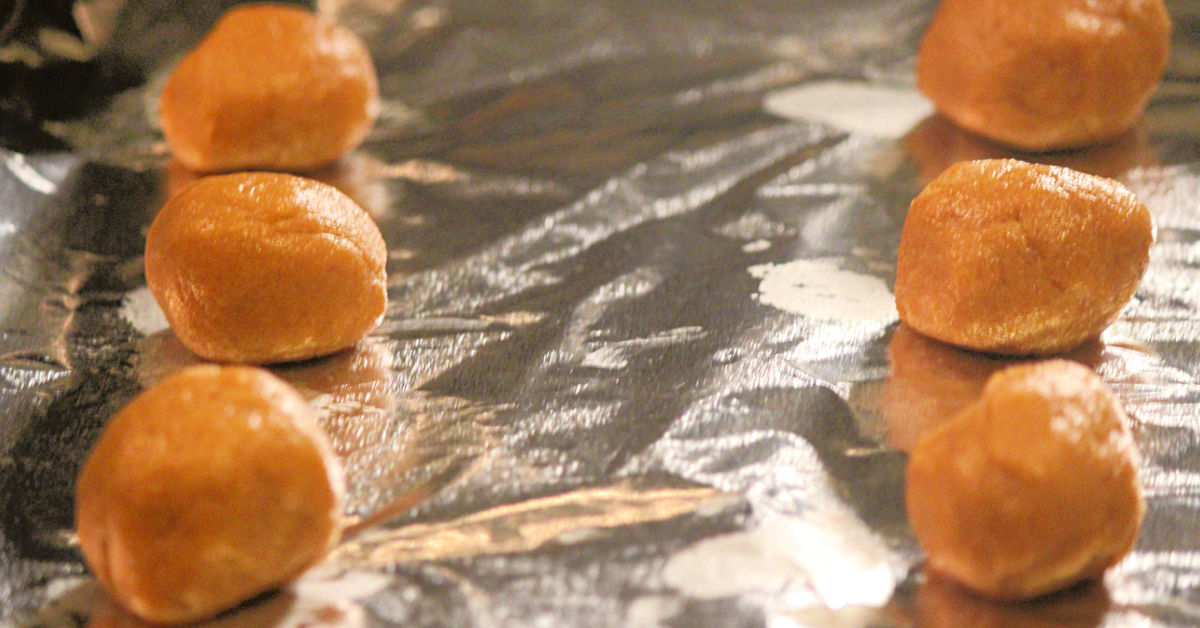 Gluten free peanut butter cookie batter balls on a baking sheet.