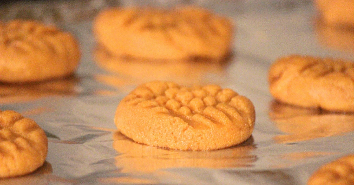 Peanut butter cookies pressed onto a cookie sheet