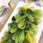 Large white platter of roasted bok choy on the dinner table