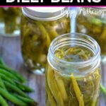 Open open and four closed pint jars of dilly beans on a table wiht some fresh green beans