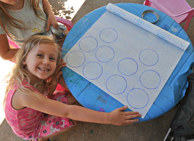 Circles traced on contact paper with the girls sitting at a blue plastic kids table