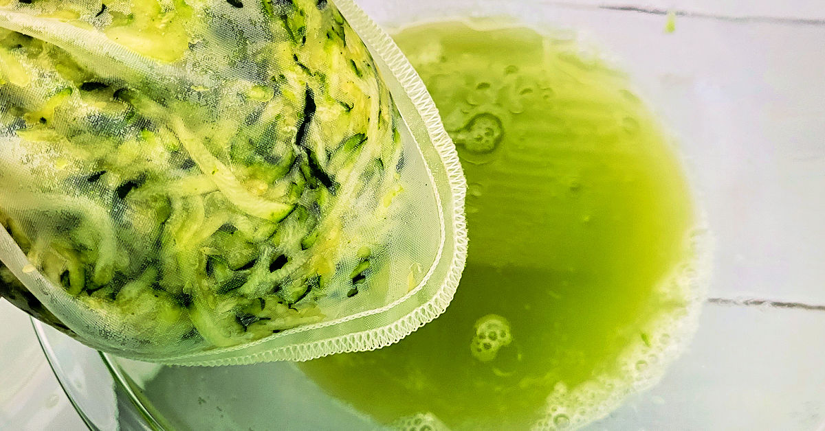 Excess water being squeezed from shredded zucchini while in a nut milk bag.
