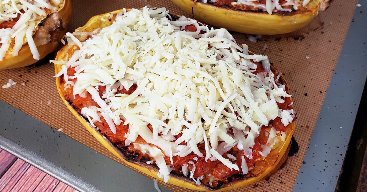 Grated mozzarella cheese spread over top of spaghetti squash lasagna boats.