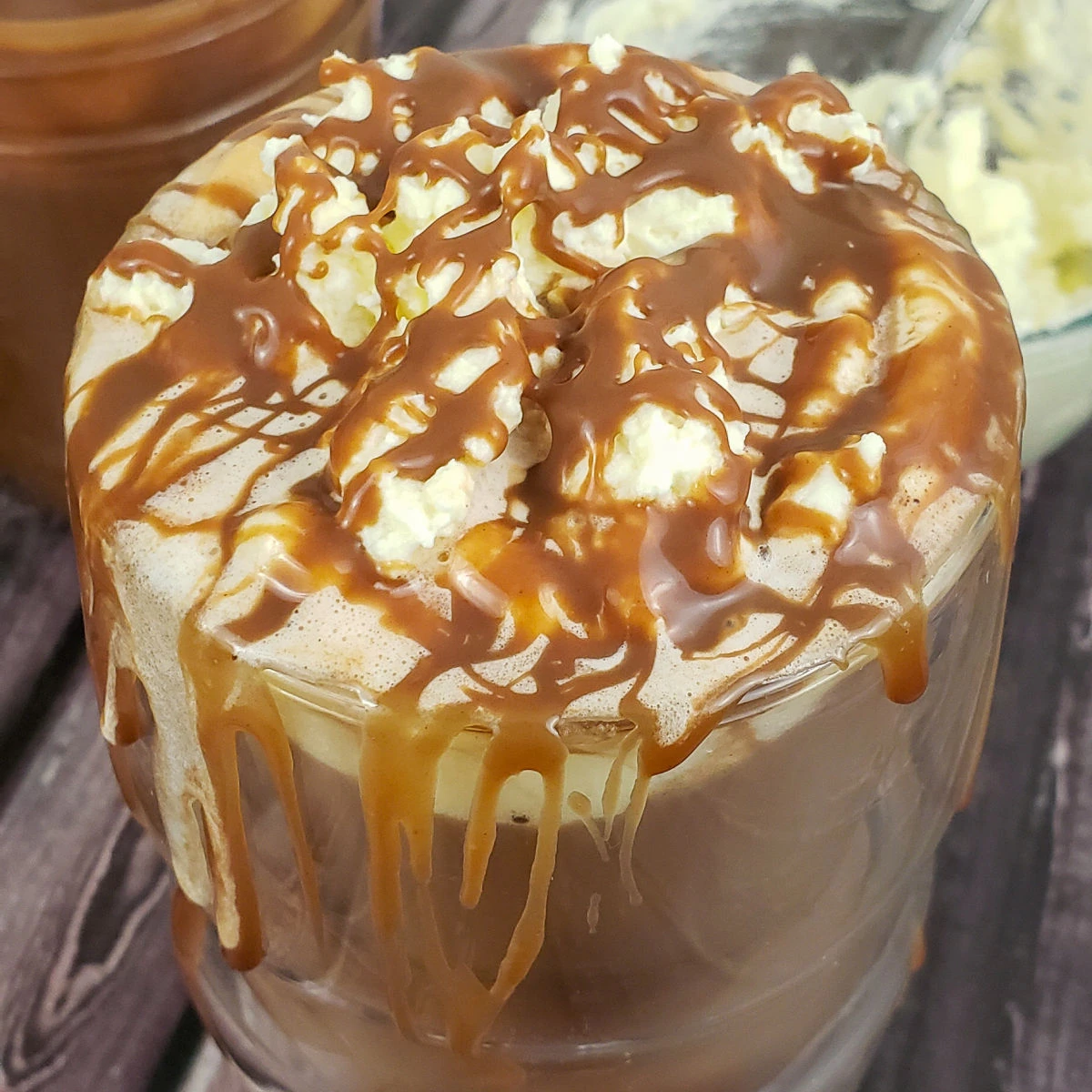 Close up of hot chocolate topped with whipped cream and caramel sauce.