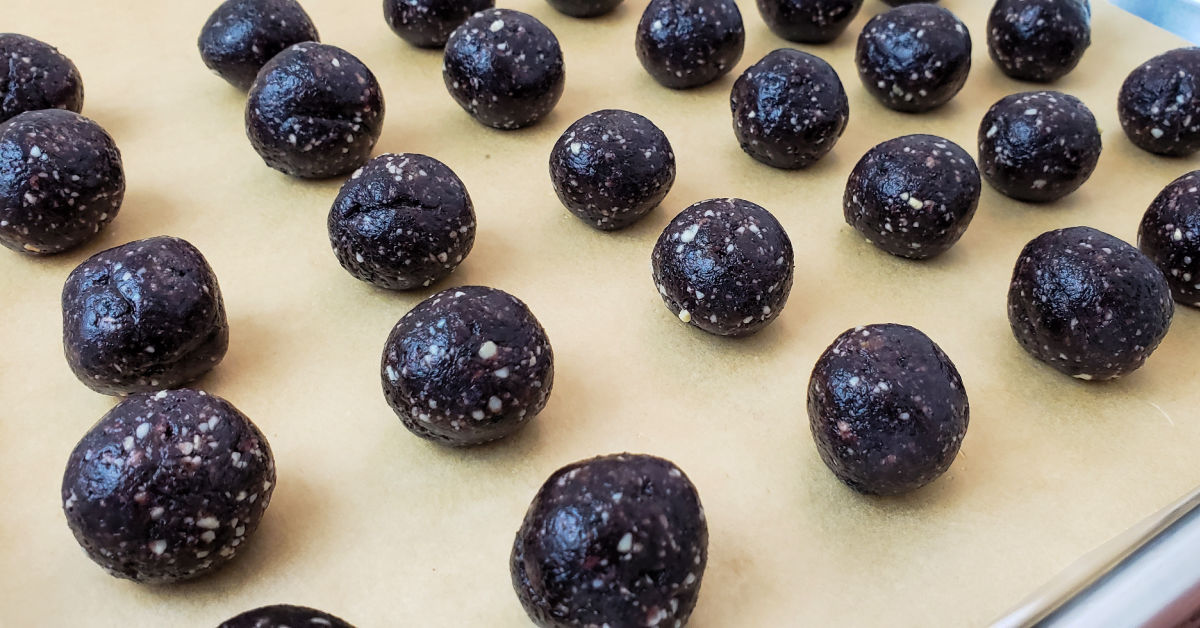 Date energy balls spread out on a parchment paper lined cookie sheet.