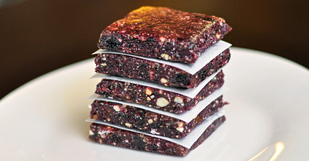 Blueberry Cashew Date Energy Bars stacked on a white plate.