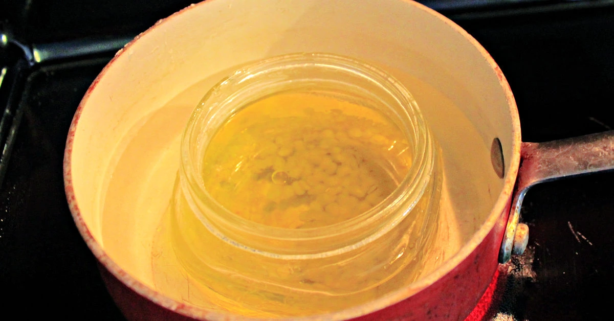 Melting furniture polish ingredients in a jar in a pan of water.