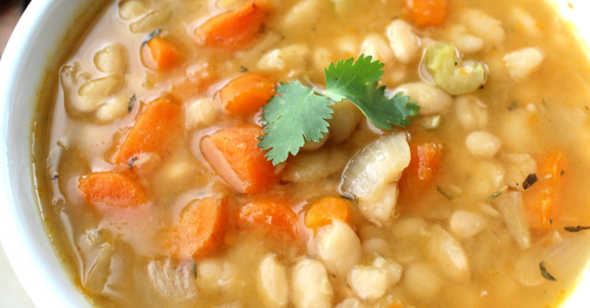Close up of Slow Cooker Navy Bean Soup with a sprig of cilantro.