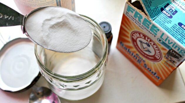 Baking soda in a tablespoon over a glass jar on a white counter