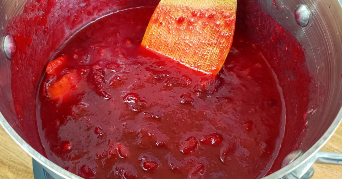 Cooked cranberry sauce in saucepan on stove.