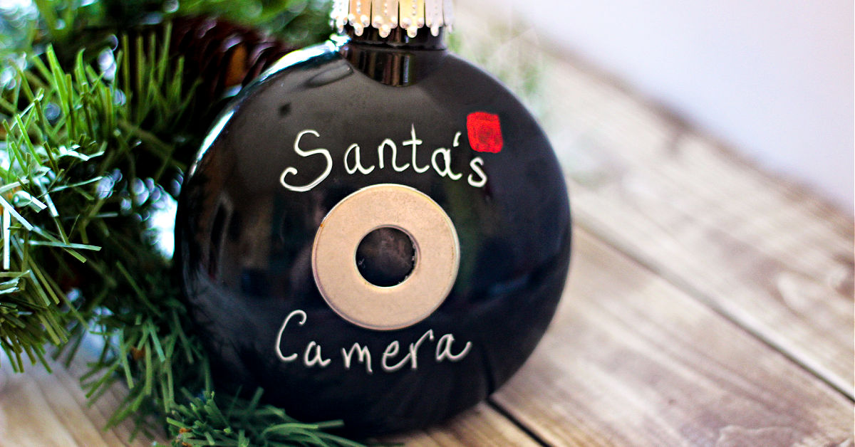 Finished Santa Cam ornament on a table next to an artificial Christmas tree branch