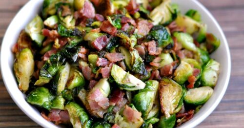 Bowl of delicious bacon and brussels sprouts on a wood table