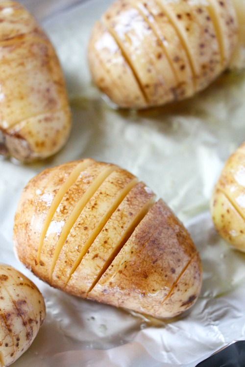 Hasselback sliced potatoes on a baking sheet before being placed in the oven