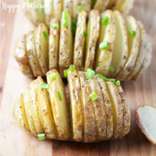 Close up of a couple of Hasselback Potatoes sitting on a cutting board ready to be served