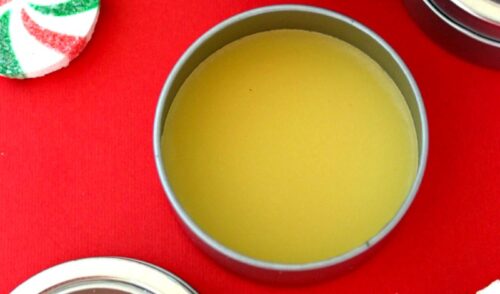 Homemade peppermint lip balm ready to use on a red table