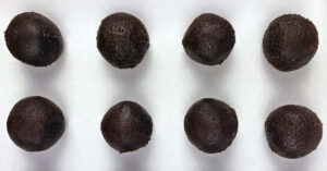 Chocolate ganache balls laid out on a parchment paper lined cookie sheet.