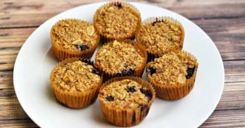 7 baked oatmeal blueberry muffins on a white plate