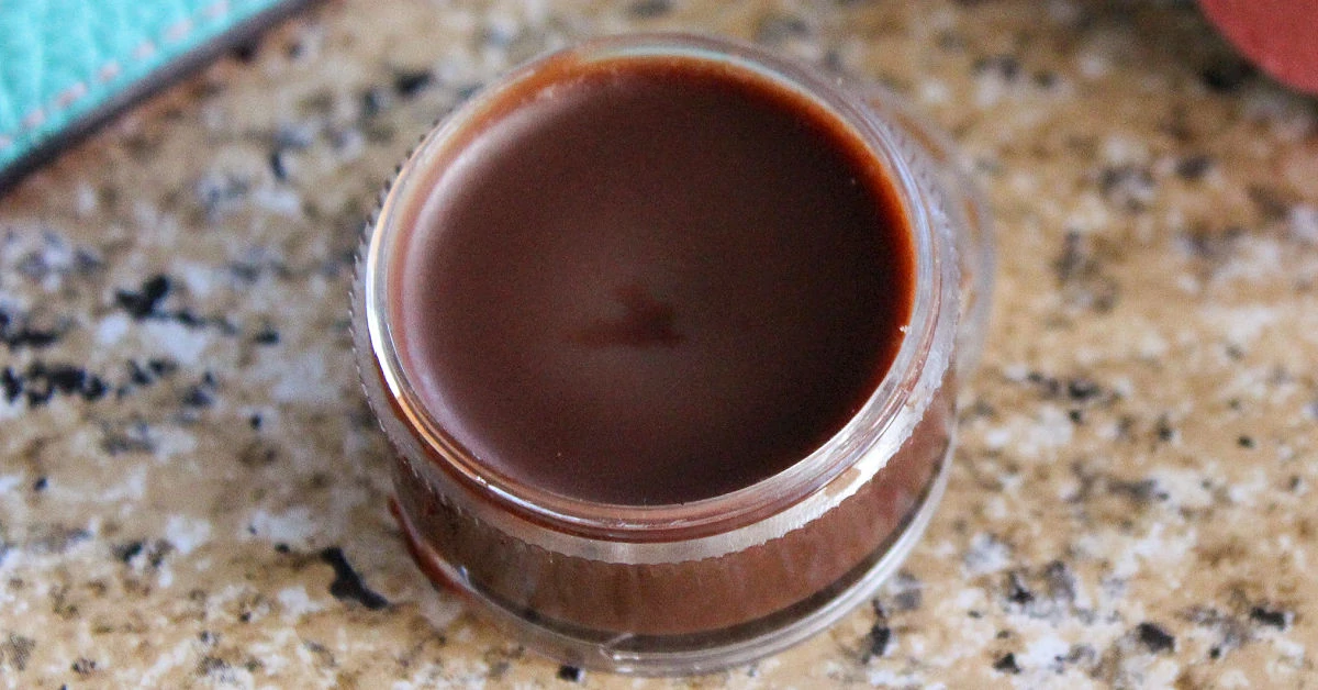 Chocolate lip balm in a small plastic lip balm pot.