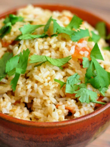 Bowl of Spanish Rice garnished with chopped fresh cilantro with label that reads, "Best Instant Pot Spanish Rice."