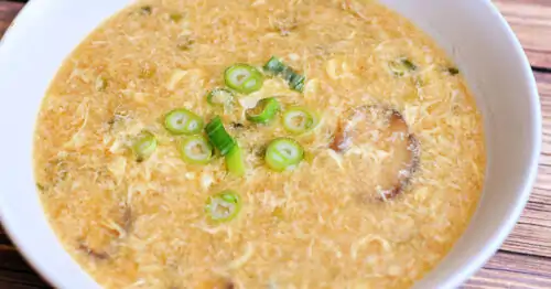 Egg Drop Soup garnished with green onions and served in shallow white soup bowl.