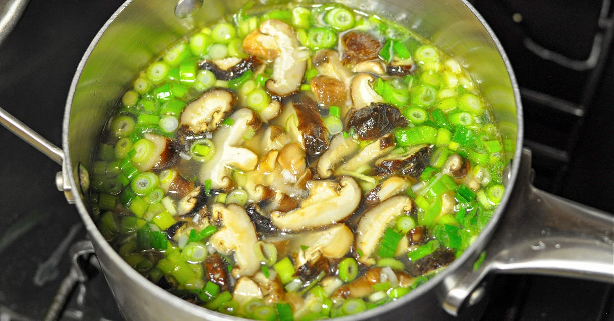 Shitake mushrooms and green onions simmering in chicken broth.