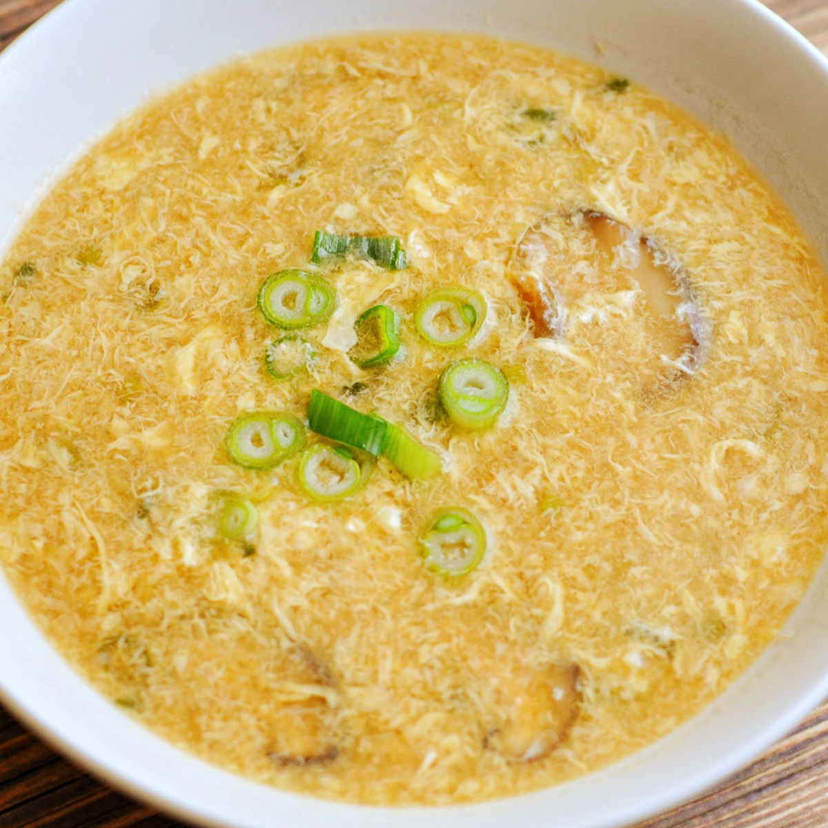 Close up of homemade egg drop soup in white bowl.
