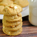 Stack of homemade white chocolate macadamia nut cookies on a table with milk