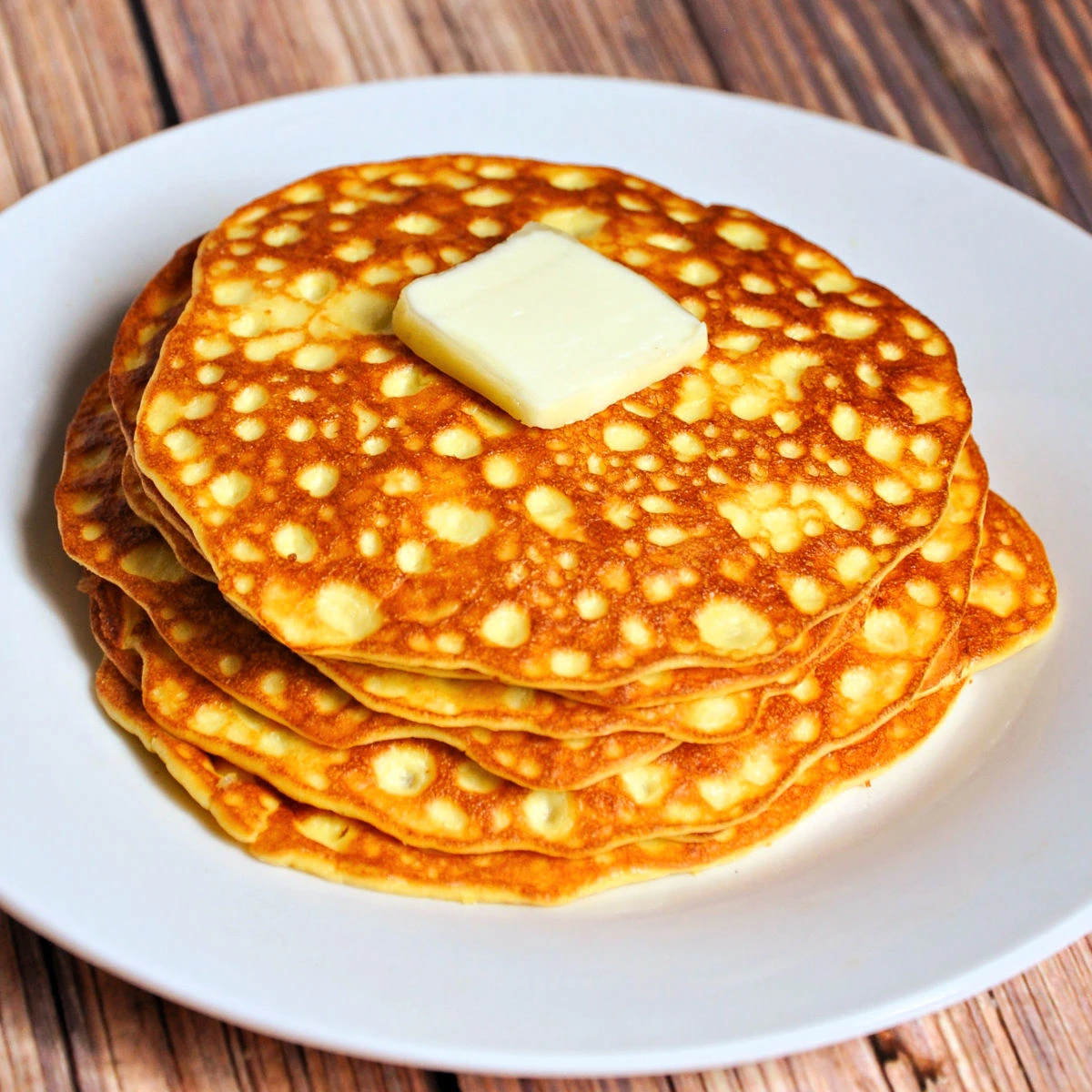 Close up of stack of low carb pancakes on a white plate with a pat of butter