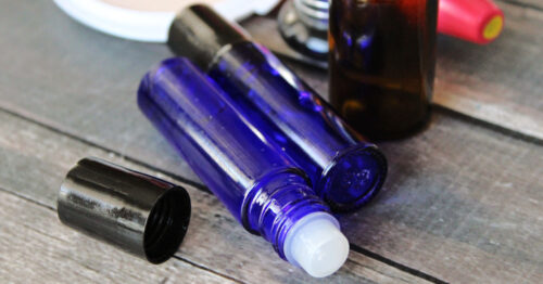 Two bottles of homemade lip gloss on a wood table.