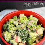 Red bowl of broccoli salad with a creamy homemade dressing, set on a light blue towel