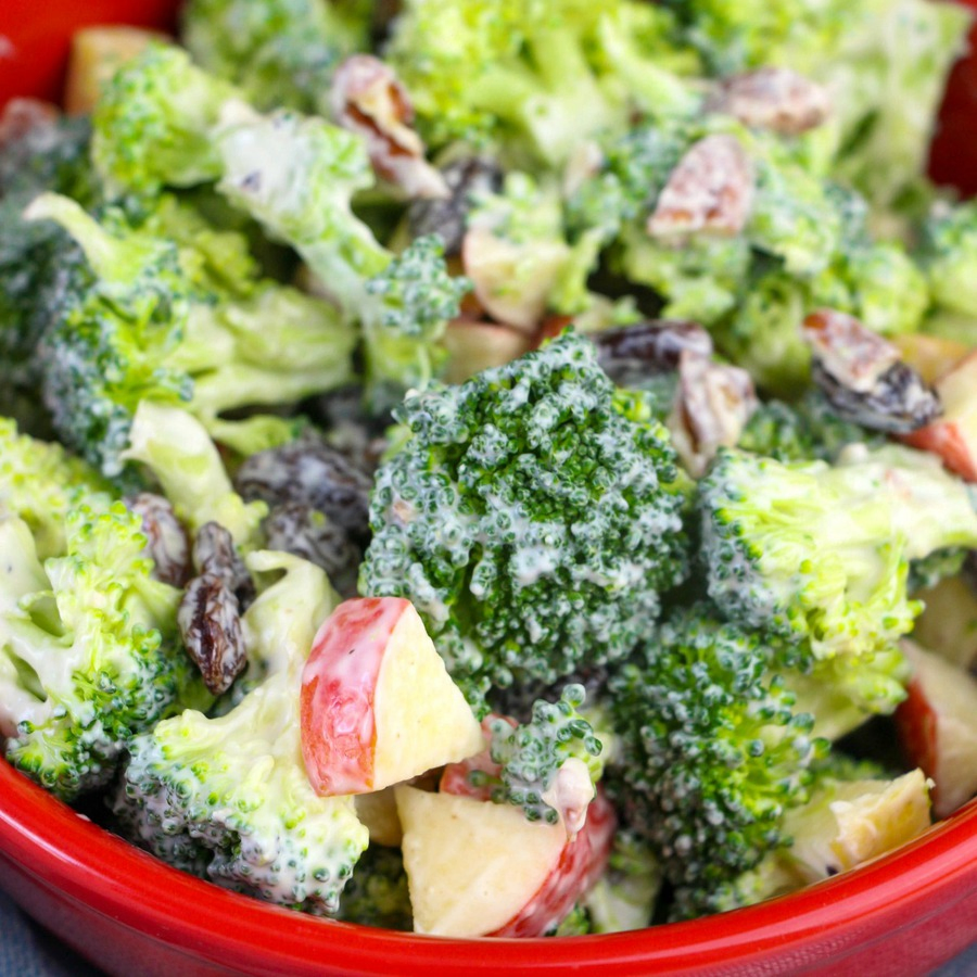 Super close up view of chunky broccoli salad with apple chunks, raisins and creamy dressing